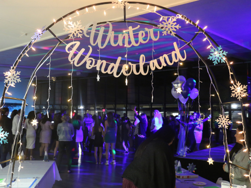 Arch with snowflakes and lights over the entrance to a community center room with a winter wonderland sign on it.