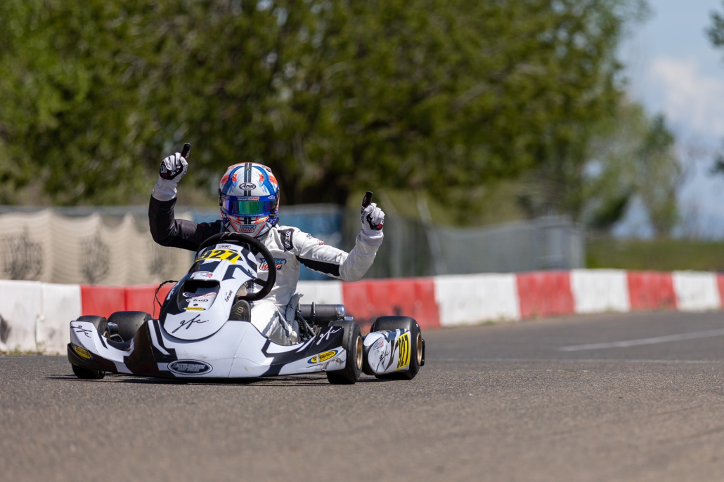 Chase holds up his arms in celebration as he rides his go kart.