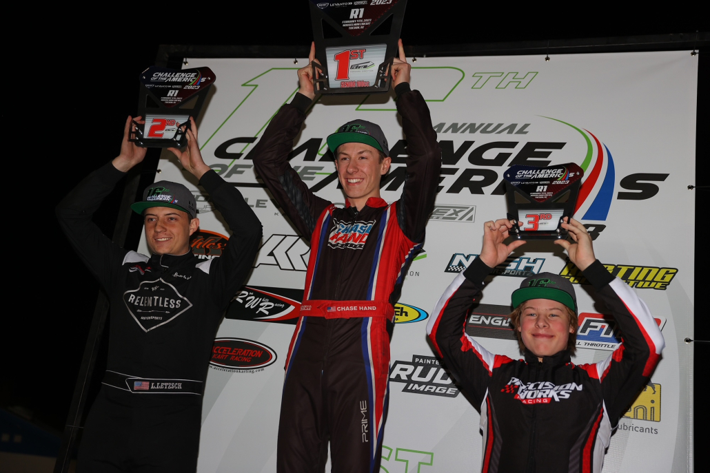 Chase stands center on a podium holding up his first place award.