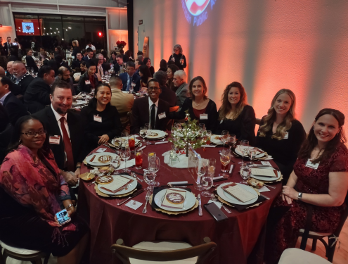 A group of Visions staff in formal attire sit around a circular table and smile for a photo at the Asian Pacific Islander American Public Affair's National Unity Awards Gala.