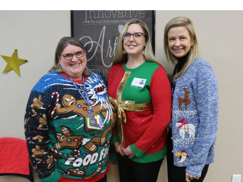 Loretta, Jessica and Kim stand together and pose for a photo wearing Christmas sweaters.