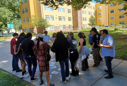 Visions students and teachers gathered in a circle outside at Sacramento State University.
