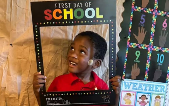 Visions students holding a frame around his face that says "First Day of School"