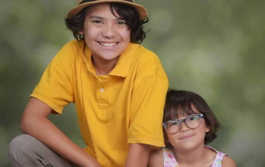 Brother and sister smiling next to eachother.