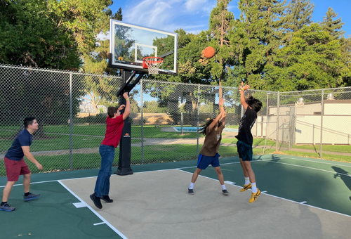 Visions students playing basketball at an outdoor court at Sacramento State University.