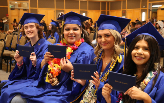 Group of Visions graduates at graduation holding up their diplomas.