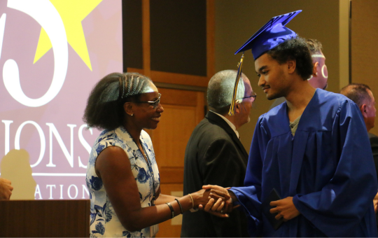 Visions graduate shaking a principal's hand on the stage at graduation.