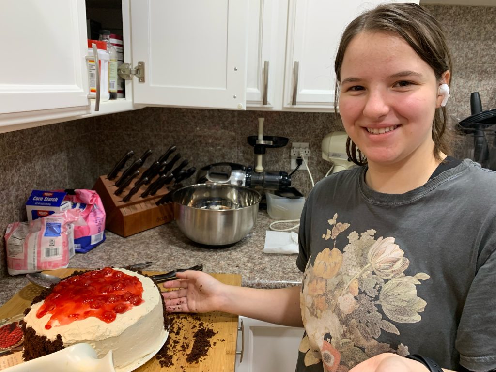 Ellie C. stands next to a cake