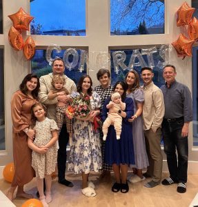 Visions graduate in photo with her family with a sign in the back that says "Congrats"