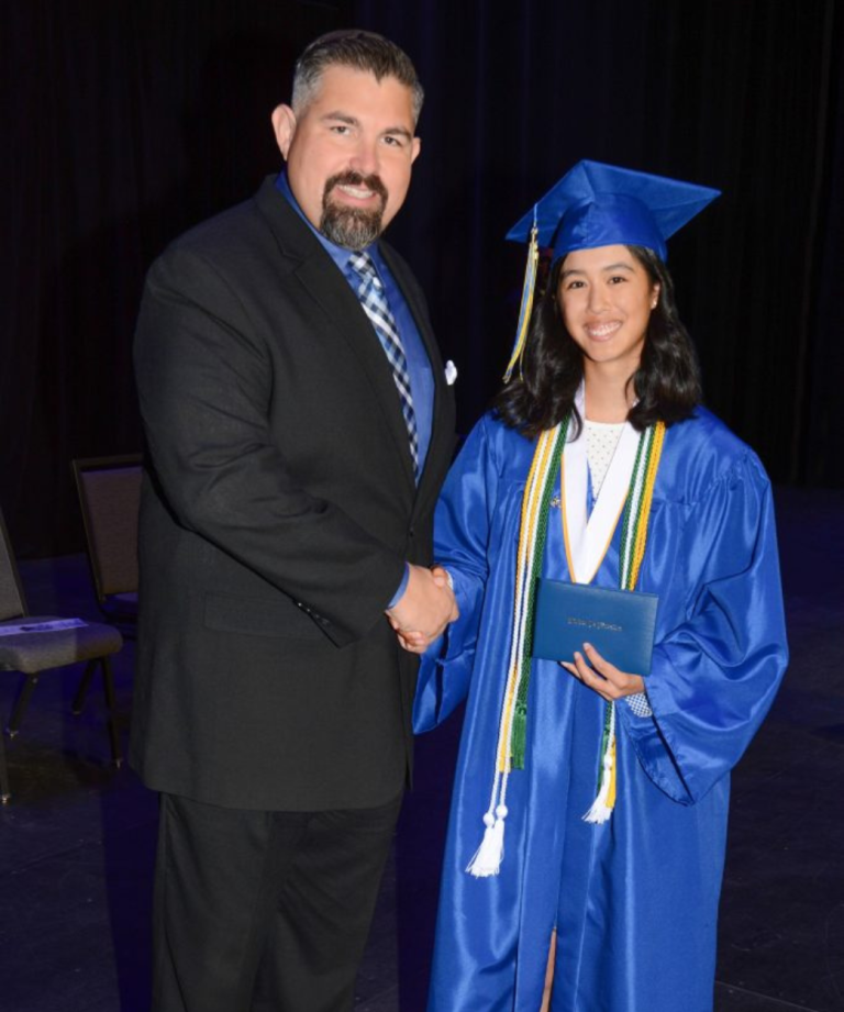 Visions graduate shaking hands with Chief Academic Officer Micah Studer.