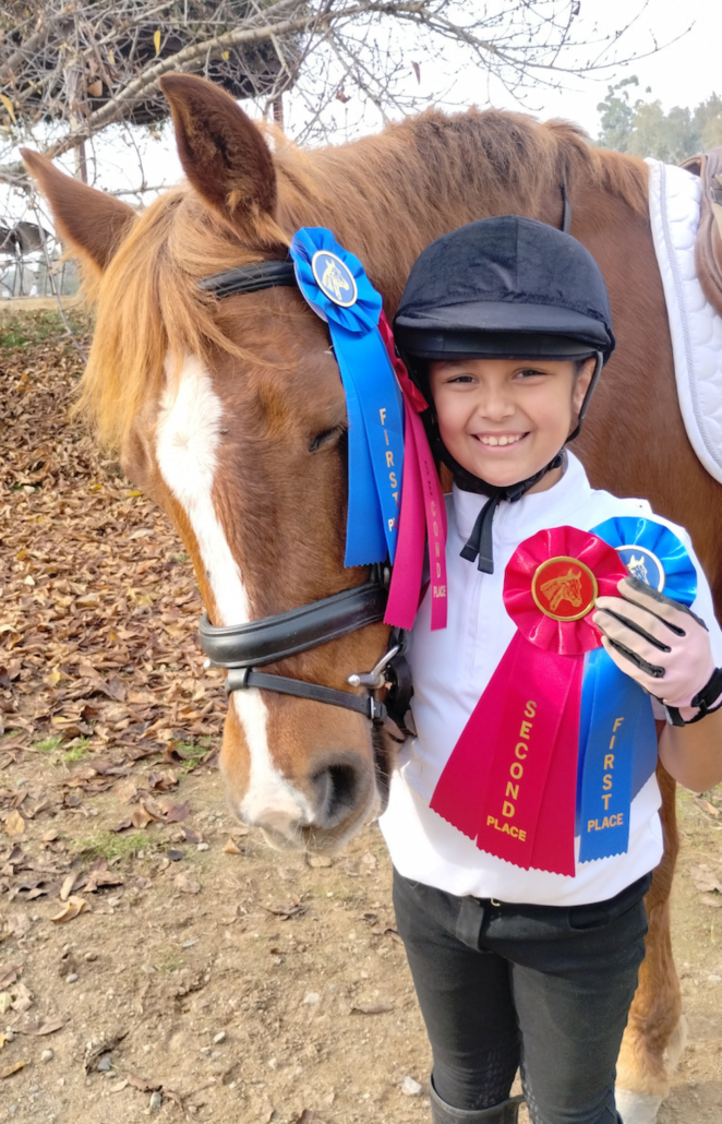 kai'lea poses with her horse Penny and winning ribbons