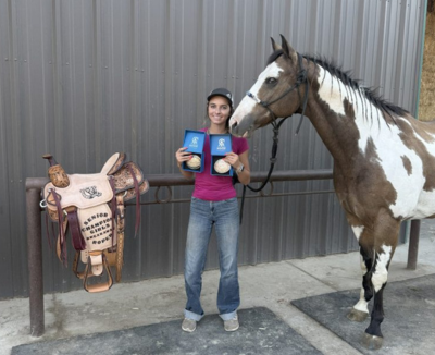 Jackie M. poses with horse and ribbons while attending a rodeo competition
