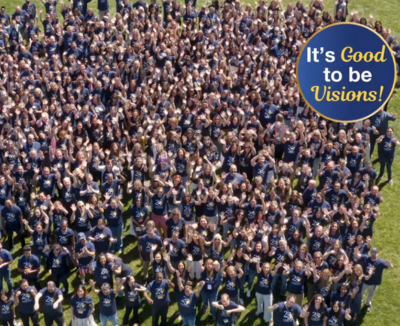Overhead photo of staff waving up to a camera in matching navy blue shirts
