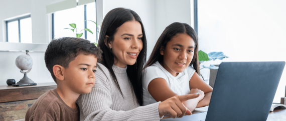 Mother pointing at laptop with two children looking on