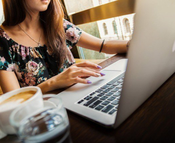 Woman working at a computer with coffee