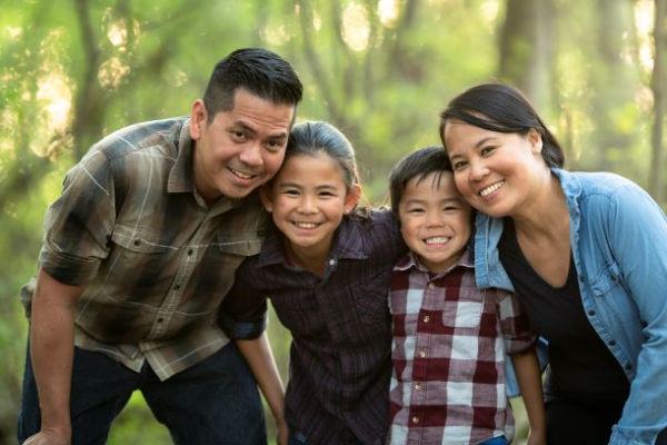 Filipino mom and dad pose outside with two young kids, one girl and one boy