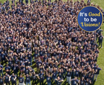 Overhead photo of staff waving up to a camera in matching navy blue shirts