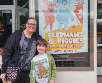 A Visions parent poses with her son (Visions student) in front of the poster for Elephant & Piggie's We're In a Play! show.